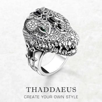 The Crocodile Head Ring features detailed silver craftsmanship, gemstone accents, and vivid green eyes. Text: THADDAEUS CREATE YOUR OWN STYLE.