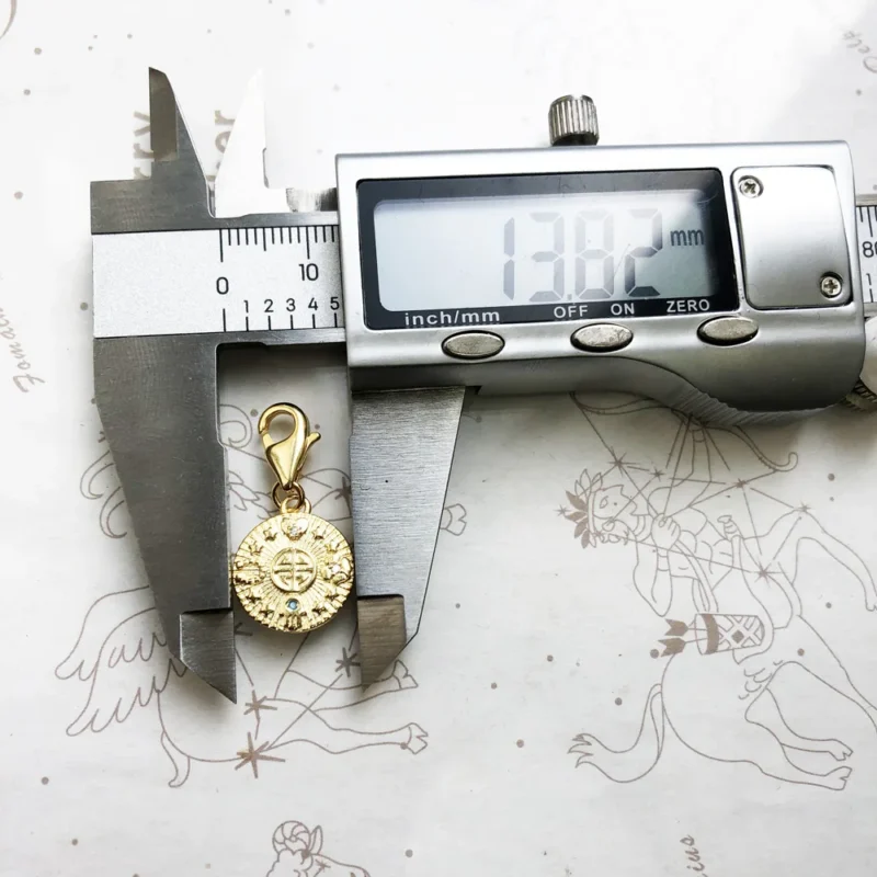 The Golden Lucky Coin Charm for Women, made of 925 sterling silver with a vintage pendant design, features engraved patterns, a central symbol, gemstones, and a lobster clasp.