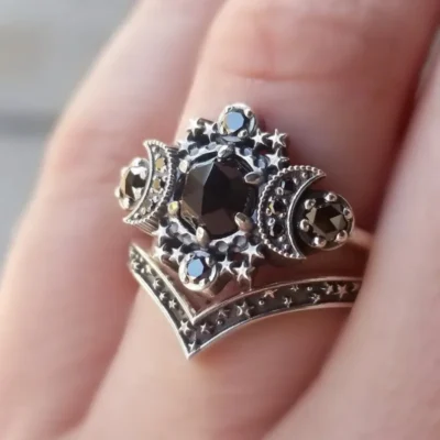 A close-up of the Moon Ring Set, showcasing a black gemstone center with crescent moon and star details, plus intricate silver designs, worn on a finger.