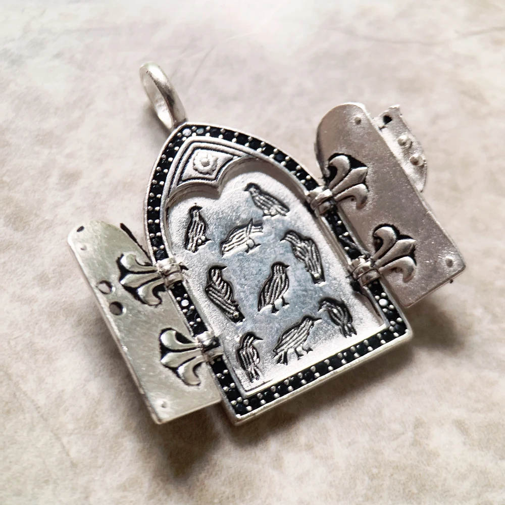 A Vintage Window Pendant shaped like a medieval arched door features engraved birds and shield details
