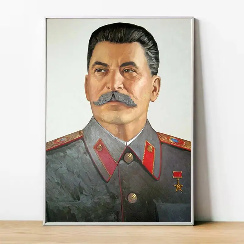 The Vintage Lenin and Stalin Portrait Posters show Stalin in a gray military uniform with red accents and medals, dark hair, and a large mustache, displayed on a wooden surface against a white wall.