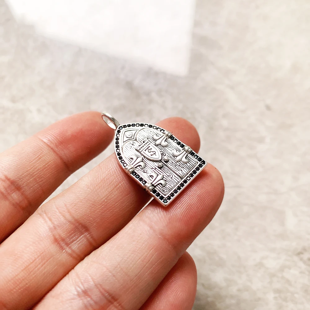 A Vintage Window Pendant shaped like a medieval arched door features engraved birds and shield details