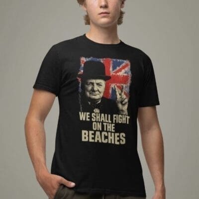 A person wearing the Winston Churchill T-Shirt – We Shall Fight on the Beaches, featuring Churchill’s V-sign, a Union Jack backdrop, and the famous quote: We shall fight on the beaches.