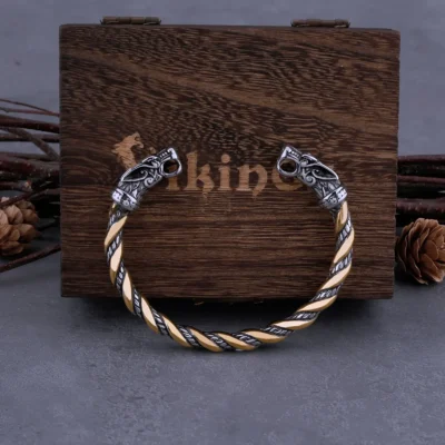 The Viking Dragon Head Cuff Bracelet features ornate dragon heads and a vintage twisted design in gold and silver colour stainless steel. Displayed before a "Viking" box, pinecones and twigs enhance this bold men's punk hip hop jewellery.